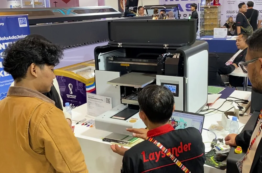 Pengunjung Menyaksikan Demonstrasi Printer Uv Di Booth Laysander Pada Surabaya Printing Expo 2026 Untuk Melihat Inovasi Teknologi Cetak Secara Langsung.