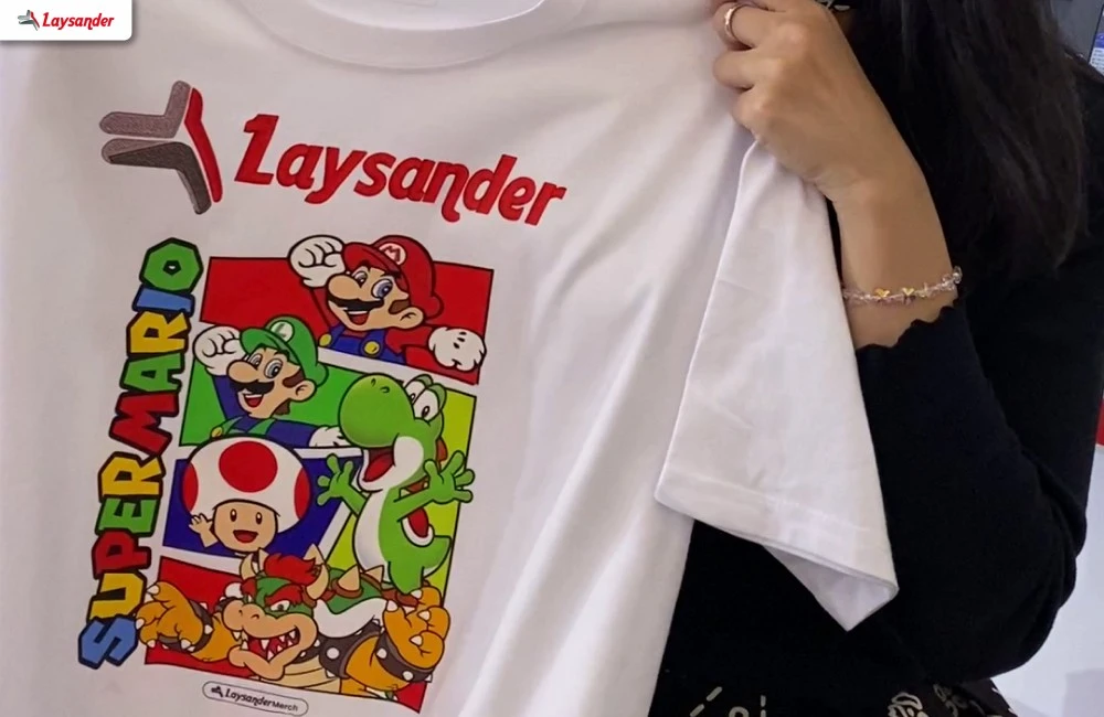 T-Shirt Eksklusif Laysander Dengan Desain Penuh Warna Yang Tersedia Gratis Bagi Pengunjung Melalui Promo Khusus Di Iape Bandung 2026.