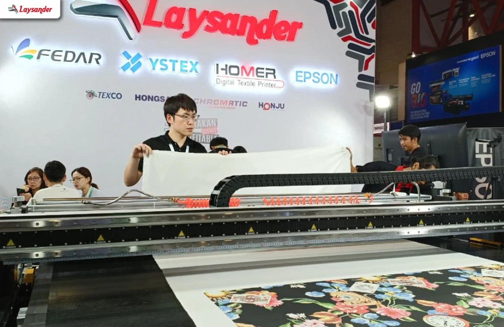 Proses Test Print Pada Mesin Printing Tekstil Di Booth Laysander Untuk Melihat Langsung Kualitas Hasil Cetak Pada Kain.