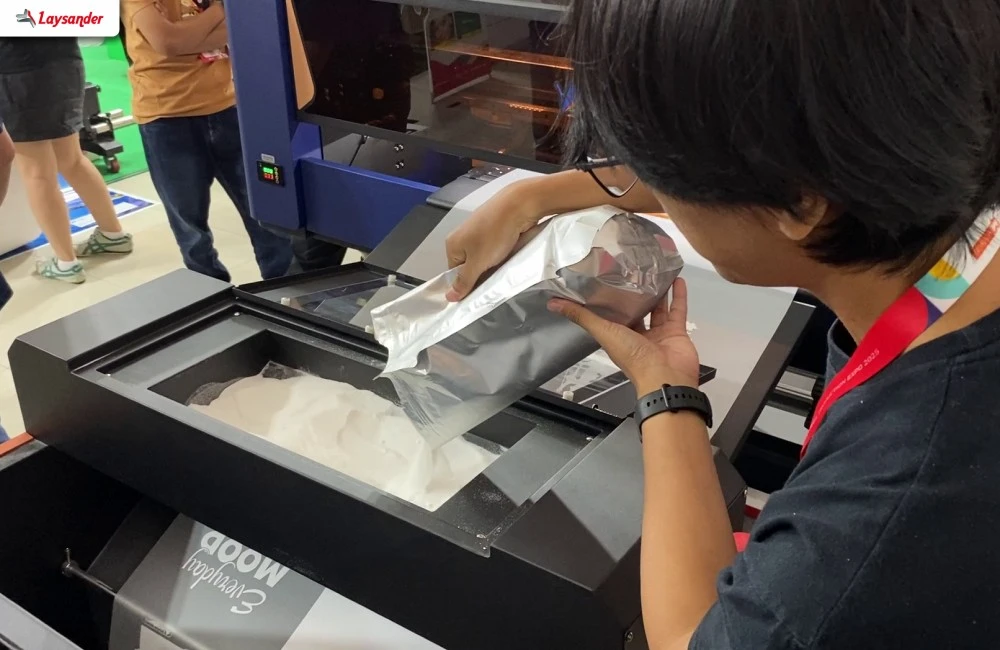 Pengunjung Melihat Langsung Proses Dan Hasil Cetak Mesin Laysander Di Allprint 2026 Melalui Sesi Demo Mesin.